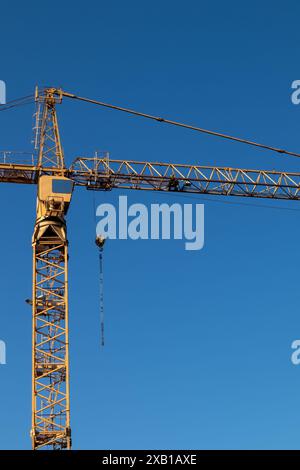 Gelber Turmkran gegen klaren blauen Himmel, Kopierraum Stockfoto