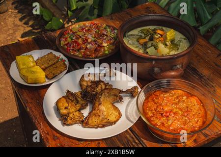 Gebratenes Hühnchen mit Cracker, serviert mit Sambal Matah, Sayur Lodeh und Tahu tempe, indonesisches Gericht Stockfoto