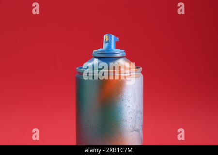 Eine Dose helle Sprühfarbe auf rotem Hintergrund, Nahaufnahme Stockfoto