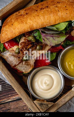 Steak-Sandwich mit Saucen und Pommes frites auf Holztisch Stockfoto