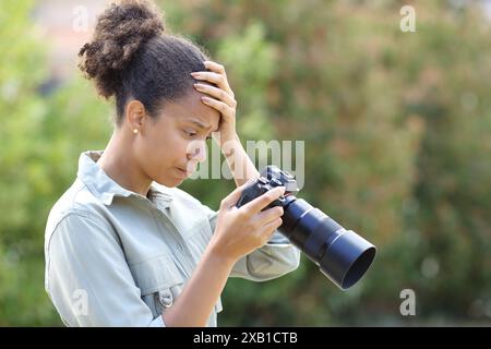 Profil eines frustrierten Schwarzweißfotografen, der das Ergebnis auf der Kamera überprüft Stockfoto