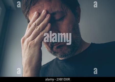Hoffnungsloser enttäuschter Mann im dunklen Zimmer, selektiver Fokus Stockfoto