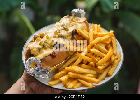 Teller philly Cheesesteak mit Käsesauce und Pommes Frites, im Outdor-Thema, grünes Blatt als Hintergrund Stockfoto