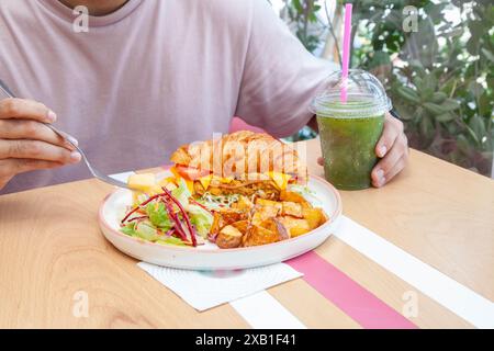 Mann isst Brioche Croissant Sandwich mit Minzlimonade Drink in einem Café. Stockfoto