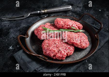 Ungekochte Frikadellen aus Hackfleisch, rohe Fleischschnitzel. Schwarzer Hintergrund. Draufsicht. Stockfoto