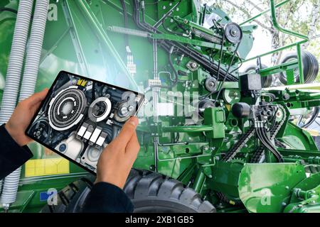 Servicemitarbeiter mit digitalem Tablet neben Mähdrescher mit offener Motorhaube Stockfoto