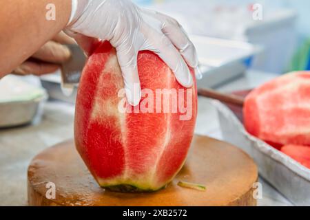 Abgeschnittene handgeschälte Wassermelone auf Schneidebrett Stockfoto