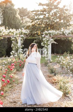 Glückliche Frauen im Garten mit Rosen, die einen fließenden blauen Schiefer tragen Stockfoto