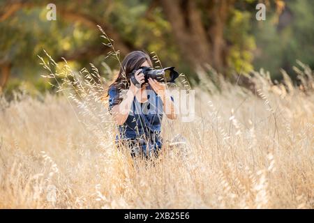 Frauen, die Fotos in hohem totem Gras machen, kniend Stockfoto