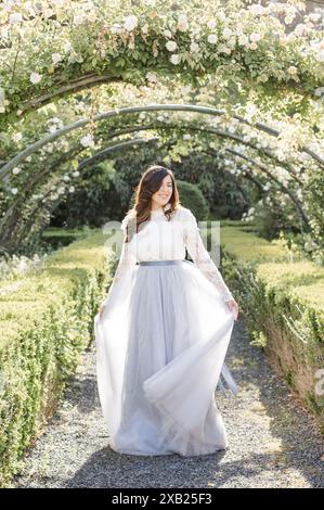 Frauen im Garten, die ihr blaues Kleid mit den Händen schweben Stockfoto