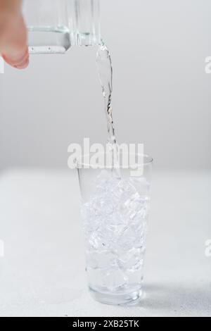 Nahaufnahme eines Wassers, das von der Hand einer Frau in ein Glas gegossen wird Stockfoto