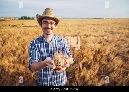 Porträt eines glücklichen Bauern auf seinem Weizenfeld. Er ist zufrieden mit der Ernte. Stockfoto