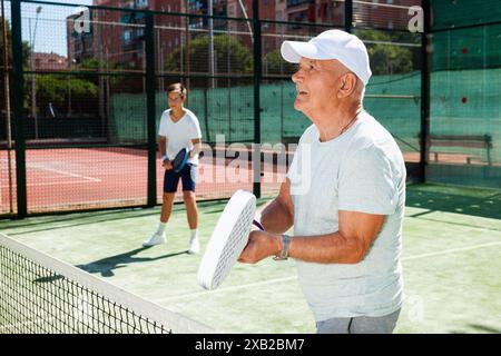 Reifer Mann und junger Mann spielen Padel Court Stockfoto