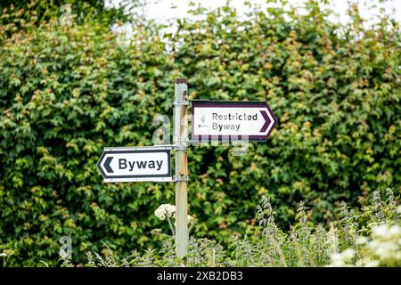 Wegweiser zum Richtungsweg und Restricted Byway an einem rostigen Metallpfosten in der Landschaft von Wiltshire Stockfoto