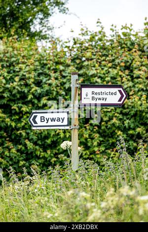 Wegweiser zum Richtungsweg und Restricted Byway an einem rostigen Metallpfosten in der Landschaft von Wiltshire Stockfoto