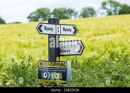 Wegweiser mit dem Richtungsweg, dem Restricted Byway und dem No Fly Tipping an einem Posten in der Landschaft von Wiltshire Stockfoto