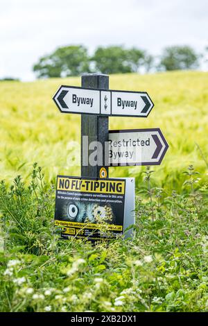 Wegweiser mit dem Richtungsweg, dem Restricted Byway und dem No Fly Tipping an einem Posten in der Landschaft von Wiltshire Stockfoto