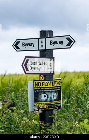 Wegweiser mit dem Richtungsweg, dem Restricted Byway und dem No Fly Tipping an einem Posten in der Landschaft von Wiltshire Stockfoto