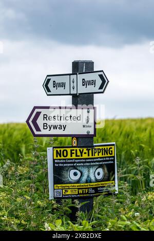 Wegweiser mit dem Richtungsweg, dem Restricted Byway und dem No Fly Tipping an einem Posten in der Landschaft von Wiltshire Stockfoto