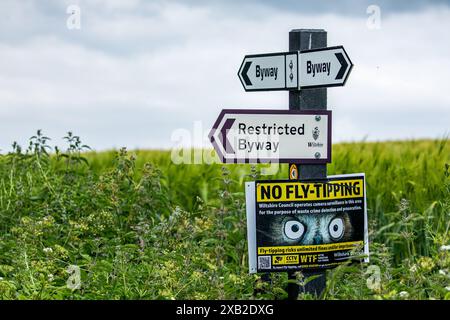 Wegweiser mit dem Richtungsweg, dem Restricted Byway und dem No Fly Tipping an einem Posten in der Landschaft von Wiltshire Stockfoto