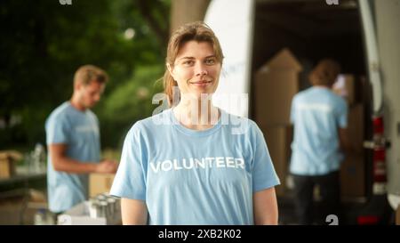 Porträt einer glücklichen hilfsbereiten jungen Freiwilligen. Schöne weiße Brünette lächelt und sieht in die Kamera. Humanitäre Hilfe, Spendenzentrum und Freiwilligenkonzept. Stockfoto