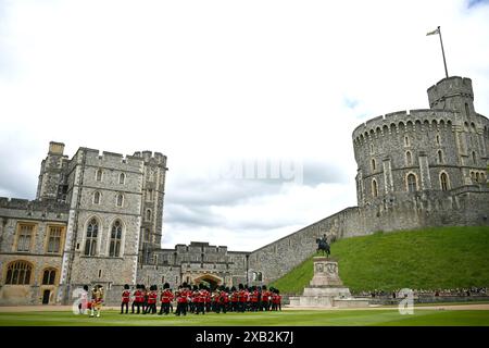 Die Band of the Irish Guards, angeführt vom Irish Guards Regimental Mascot, einem irischen Wolfshund namens Seamus (Turlough Mor), der vor König Charles III, Oberst der Household Division, marschiert und der No 9 und No 12 Kompanie der Irish Guards neue Farben präsentiert; während einer Zeremonie in Windsor Castle, Berkshire. Bilddatum: Montag, 10. Juni 2024. Stockfoto