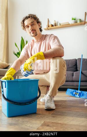 Ein gutaussehender Mann in kuscheliger Hauswäsche, der den Boden mit einem Eimer reinigt. Stockfoto