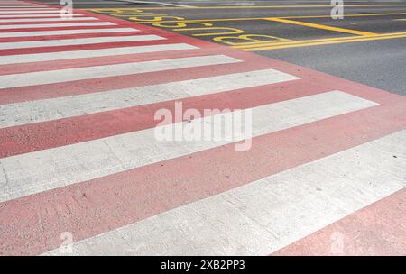 Eine lebhafte Farbpalette auf einer Zebraüberquerung in Tiflis mit roten und weißen Streifen mit angrenzenden gelben Straßenmarkierungen Stockfoto