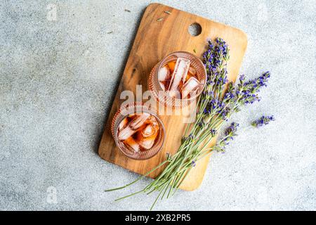 Zwei Gläser Eiscognac-Cocktail, wunderschön präsentiert mit Lavendelzweigen auf einem rustikalen Holzschneidebrett, präsentiert ein elegantes und aromatisches Stockfoto