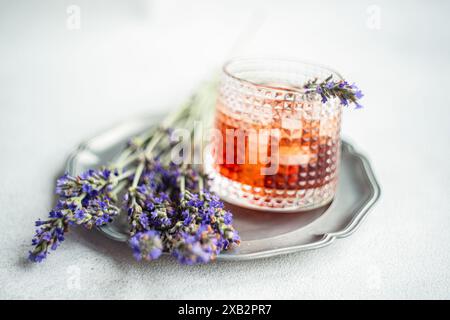 Ein raffinierter Cognac-Cocktail in einem strukturierten Glas, wunderschön garniert mit frischen Lavendelzweigen auf einem silbernen Tablett Stockfoto