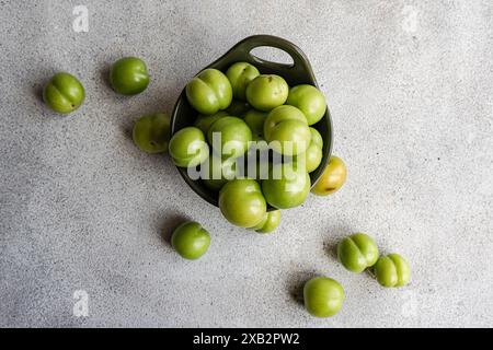 Blick von oben auf reife grüne Pflaumen aus biologischem Anbau in einer dunklen Schüssel, die häufig in Küchen im Mittelmeerraum verwendet wird Stockfoto