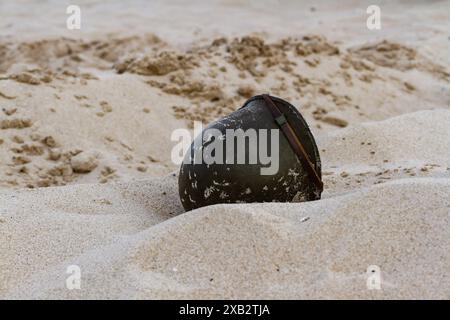 Nahaufnahme. Amerikanischer Infanteriehelm M1 aus dem Zweiten Weltkrieg am Strand. Stockfoto