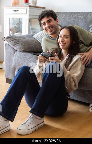 Ein fröhliches junges Paar spielt gern Videospiele in seinem gemütlichen Wohnzimmer und zeigt einen Moment der Freude und der Gesellschaft in einem komfortablen Zuhause setti Stockfoto