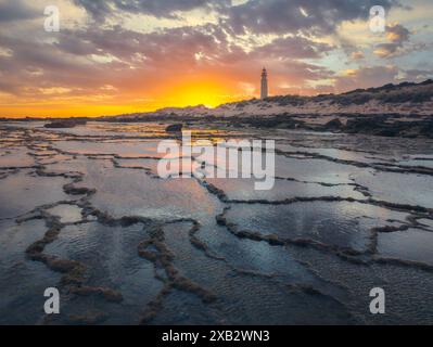 Ein ruhiger Sonnenuntergang taucht Trafalgar Lighthouse in warmen Farbtönen auf, wobei die Felsenbecken im Vordergrund die Farben des Himmels reflektieren. Stockfoto