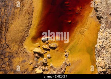 Leuchtende gelbe und rote mineralreiche Böden mit verstreuten Steinen in Riotinto, Huelva, Spanien, die die abstrakte Kunst der Natur zeigen. Stockfoto