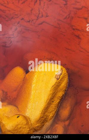 Ein eindrucksvolles Foto, das einen orangen Stein aus dem eisenreichen roten Wasser von Riotinto in Huelva, Spanien, zeigt, wie schön die natürlichen Mineralien sind Stockfoto