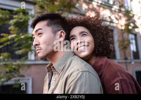 Ein multiethnisches Paar, bestehend aus einem Chinesen und einer hispanischen Frau, teilt einen intimen Moment in einer bezaubernden Straße in Madrid, Spanien. Die Frau beugt sich Stockfoto
