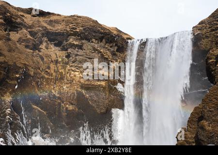 Dieses atemberaubende Bild zeigt einen mächtigen Wasserfall, der durch das felsige Gelände der isländischen Halbinsel Snaefellsnes stürzt und eine schwache Regenbogenform aufweist Stockfoto