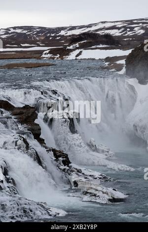 Ein spektakulärer Blick auf einen gefrorenen Wasserfall, der inmitten des schneebedeckten und felsigen Geländes in den abgelegenen Regionen Islands stürzt, mit der mächtigen Natur Stockfoto