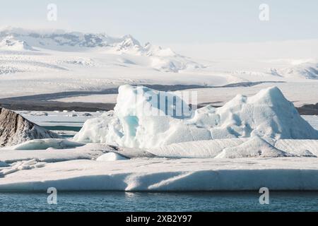 Ruhiger Blick auf die Gletscherlagune Jokulsarlon in Island mit leuchtend blauen Eisbergen vor der Kulisse verschneite Berge unter klarem Himmel Stockfoto