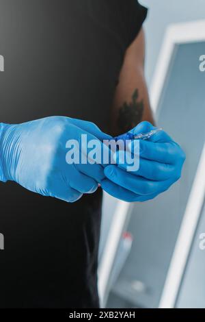 Ein nicht wiedererkennbarer Tätowierer in Ecuador mit blauen Handschuhen bereitet die Nadel auf eine Sitzung vor und zeigt den akribischen Prozess, bei dem ich dabei war Stockfoto