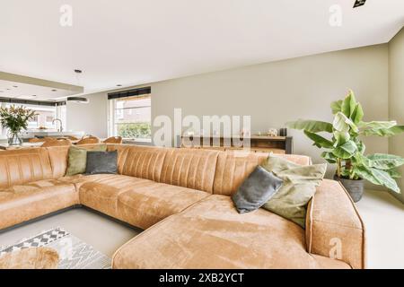 Ein geräumiges und stilvolles Wohnzimmer mit einem großen, weichen Ecksofa in einem braunen Farbton, ergänzt durch grüne und graue Kissen, hervorstehend sind ein hölzerner Si Stockfoto