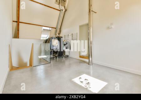 Ein geräumiges, modernes Loft mit minimalistischem Innendesign mit industriellem Touch, das durch einen freiliegenden Kanal und einen eleganten Kleiderständer veranschaulicht wird. Stockfoto