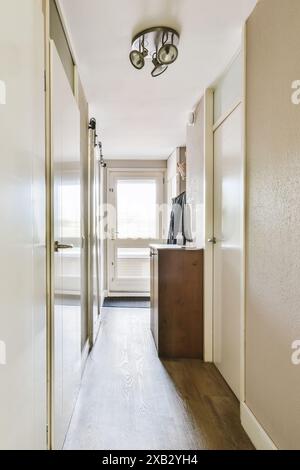 Ein eleganter und moderner Flur mit minimalistischen Designelementen, weißen Wänden, Holzböden und schicken Beleuchtungselementen. Stockfoto