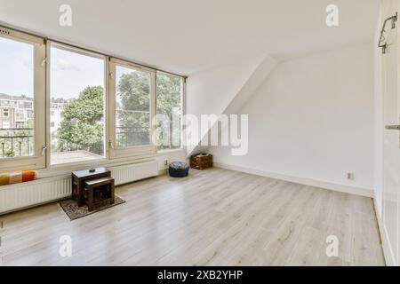 Ein luftiger, sonnendurchfluteter Dachraum mit großen Fenstern, Hartholzböden und minimalistischer Ästhetik, geeignet für Innenarchitekturen. Stockfoto