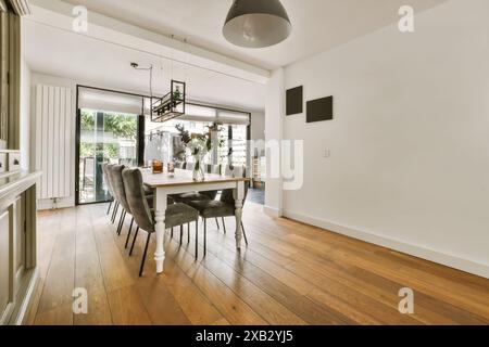 Moderner Essbereich in einem hellen, geräumigen Raum mit großen Glasschiebetüren, die sich auf einen malerischen Außenbereich in Rogg öffnen Stockfoto