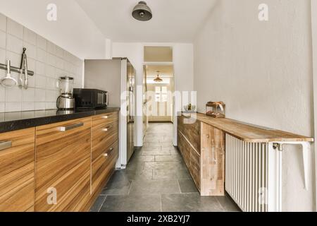 Diese attraktive Küche in Amsterdam kombiniert moderne Geräte mit rustikalen Holzschränken und eleganten schwarzen Arbeitsflächen und bietet eine reizvolle Mischung aus Stockfoto