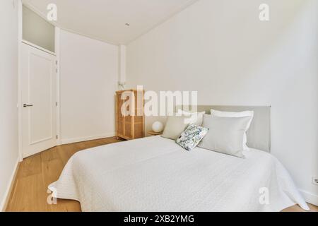 Ein ruhiges und übersichtliches Schlafzimmer mit einem großen Bett mit weißer Bettwäsche, Holzfußboden und schlichter Einrichtung in der Schippersstraat 5. Die natürliche Leichtigkeit Stockfoto