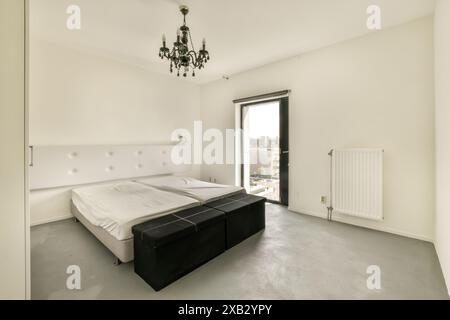 Geräumiges, gut beleuchtetes Schlafzimmer mit großem Fenster, weißer Bettwäsche und klassischem Kronleuchter im Bos en Lommerweg 276 Stockfoto