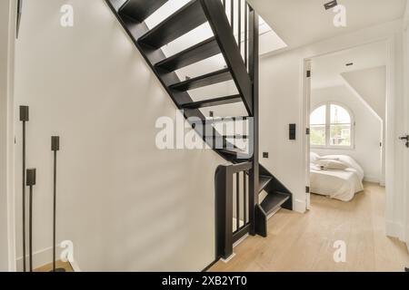 Ein zeitgenössisches Innenleben mit einer schwarzen, modernen Treppe mit einem eleganten Geländer, das in eine obere Ebene führt. Der Raum ist hell mit weißen Wänden Stockfoto